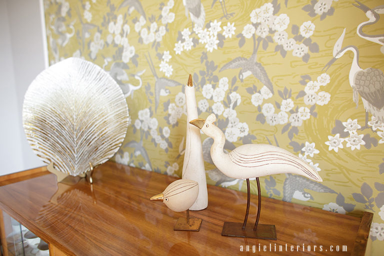 GR&J Baker Heron wallpaper in yellow and grey dining room with Mid-century modern dining set and brass accents